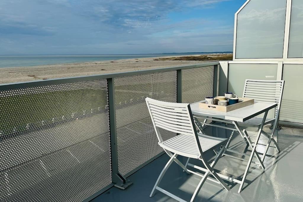 einen Tisch und zwei Stühle auf einem Balkon mit Strand in der Unterkunft Face à la mer immense in Cayeux-sur-Mer