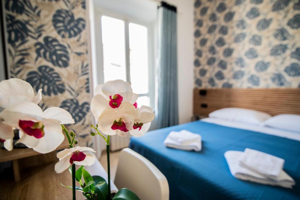 a hotel room with a blue bed and flowers at Hotel Dell'Urbe in Rome