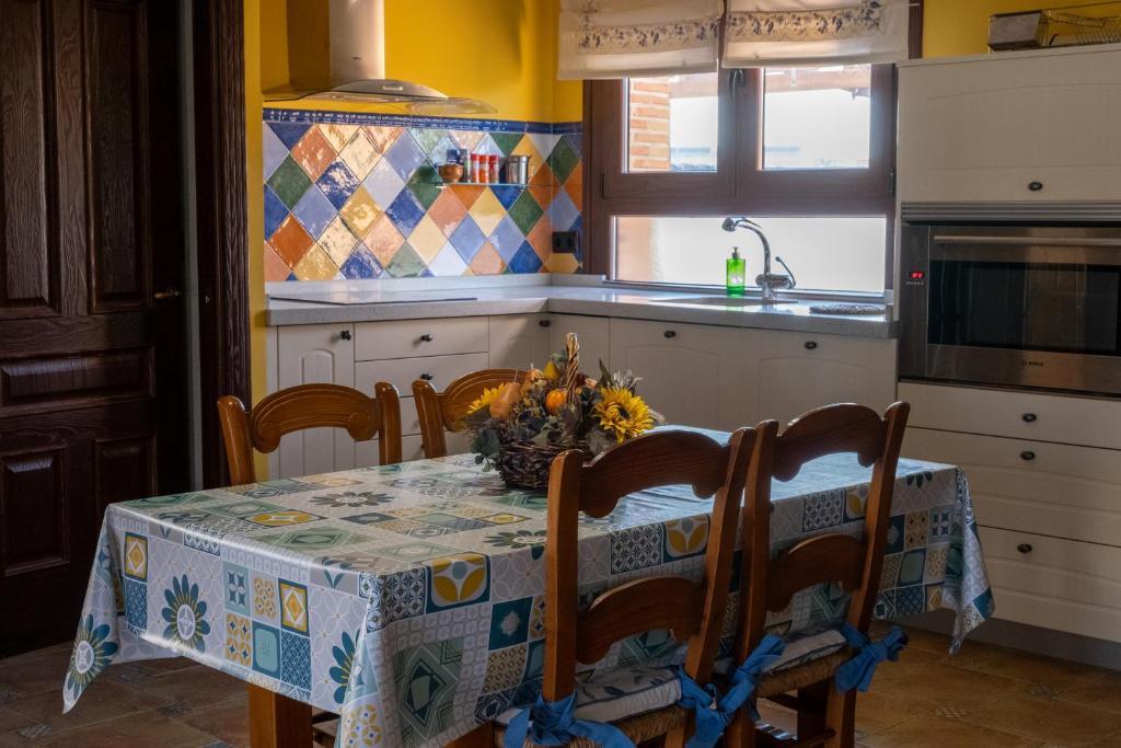 cocina con mesa, sillas y mantel en Casa el Tempranal en Yuncler