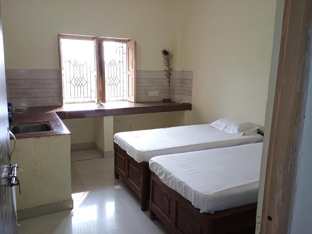 - une chambre avec 2 lits jumeaux et une fenêtre dans l'établissement Budha ashram guest house, à Bodh Gaya