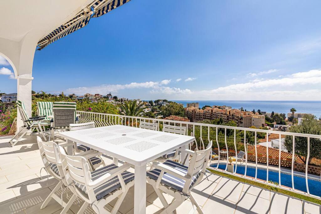 een witte tafel en stoelen op een balkon met uitzicht op de oceaan bij Villa con piscina en Fuengirola in Fuengirola