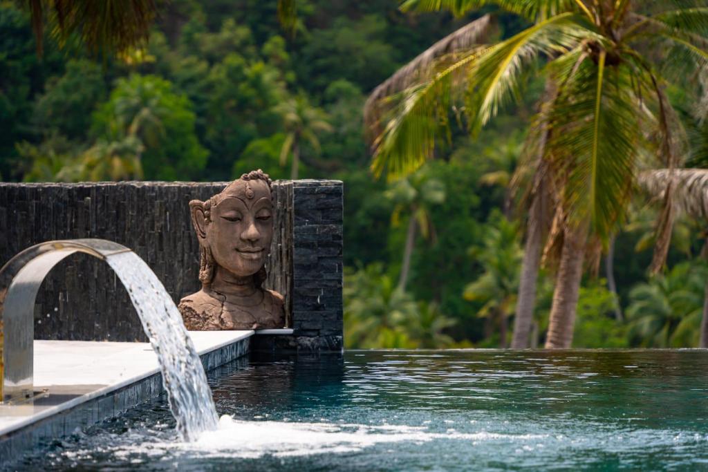 eine Statue neben einem Pool mit einem Brunnen in der Unterkunft Infinity Villa sea view sunset in Ko Phangan