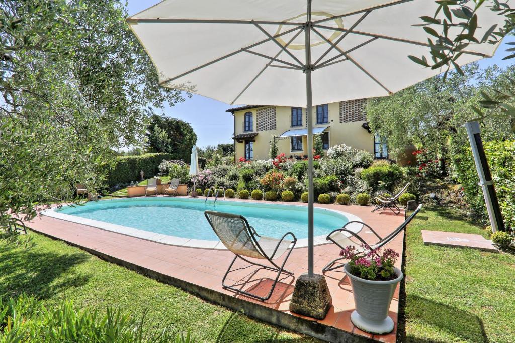 una sombrilla y sillas junto a la piscina en Villa Antica Sosta Renai, en Castelfiorentino