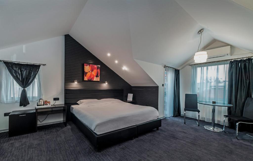 een slaapkamer met een groot bed, een bureau en een stoel bij Sienna Apartments in Skopje