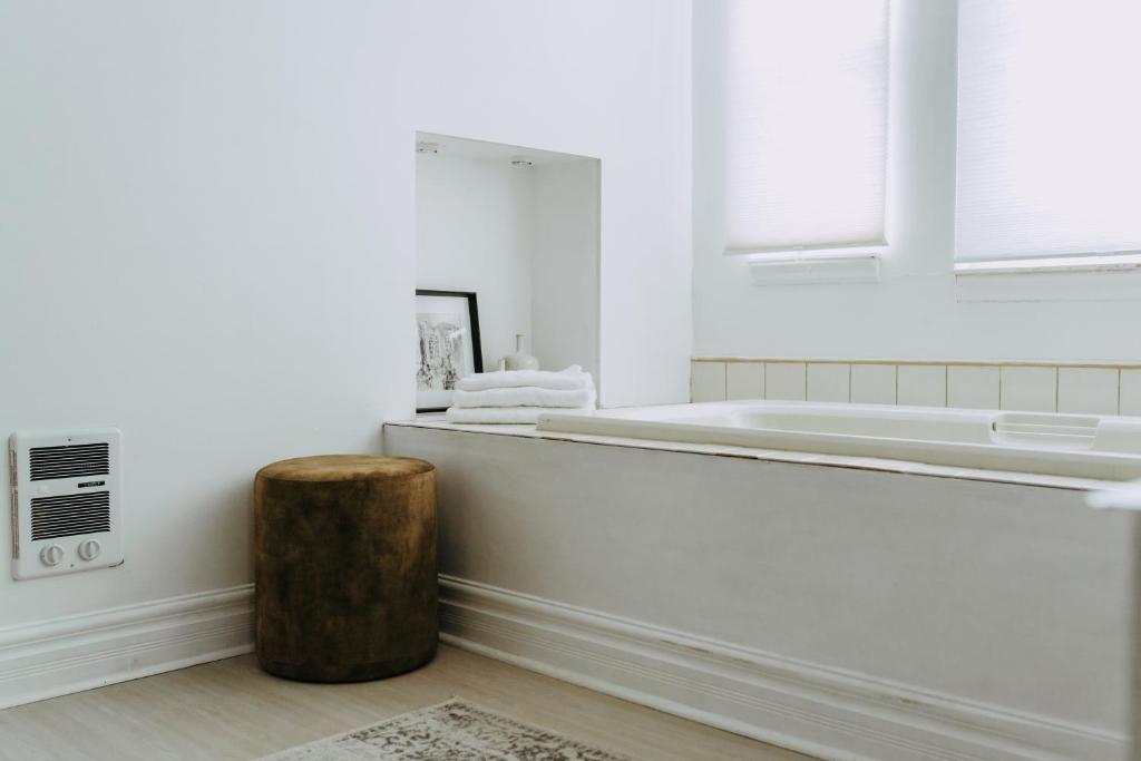 a white bathroom with a tub and a wooden stool at No. 5 East in Winnipeg
