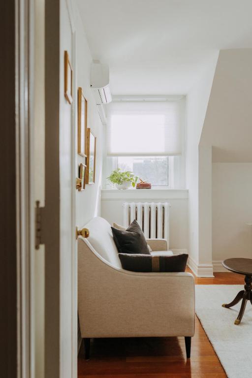 a living room with a white chair and a window at No. 5 East in Winnipeg
