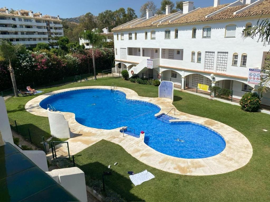 a large swimming pool in a yard next to a building at Spacious, calm and bright Duplex Apartment in Private Residence ideal for families, beach and golf in Sitio de Calahonda