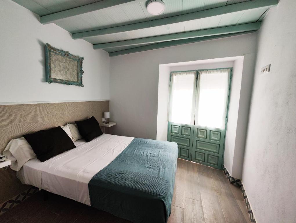 a bedroom with a bed and a green door at Apartamento PUERTA DE CÓRDOBA in Carmona