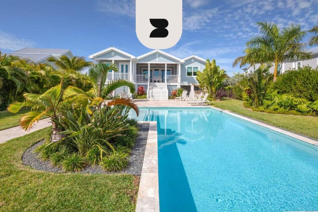 a villa with a swimming pool in front of a house at Coastal Chic by Brightwild-Pool & Boat Dock in Stock Island
