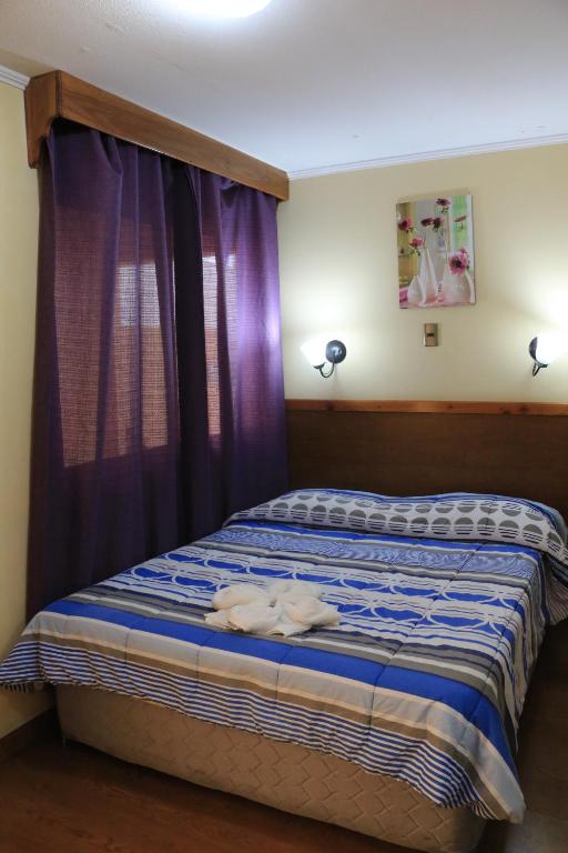 a bedroom with a bed with purple curtains at Hotel Garden Wilson in Iquique