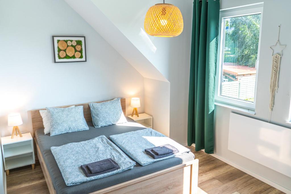 a bedroom with a bed with blue pillows and a window at Domki Przystań Kotwica in Jastrzębia Góra