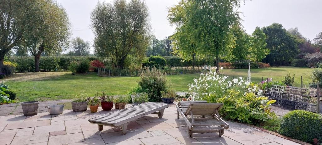 een patio met een tafel en stoelen in een tuin bij Garden Cottage in heart of Kent in Kent