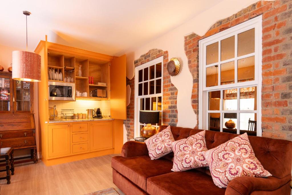 sala de estar con sofá marrón y cocina en Apartments at Number 16 - The Jolly Coopers, en Hampton