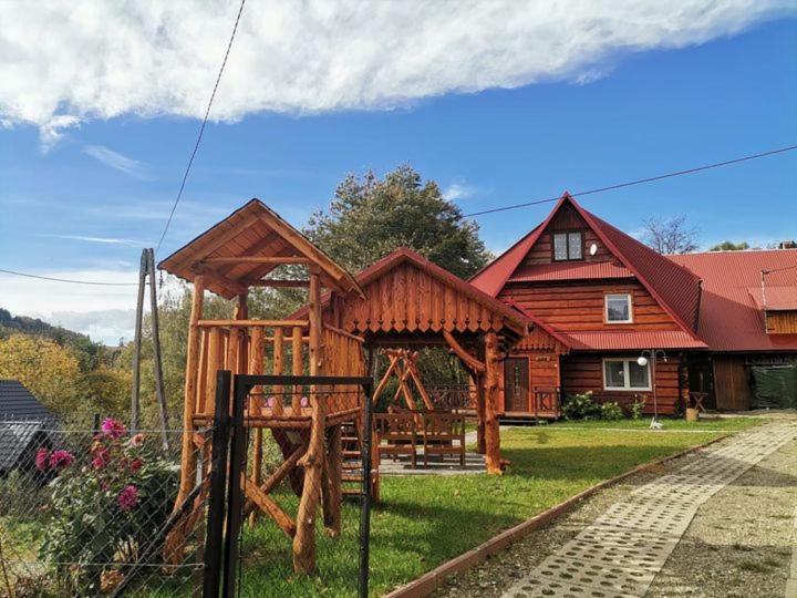 a wooden house with a playground in front of it at Dom na Smyrakach in Zawoja