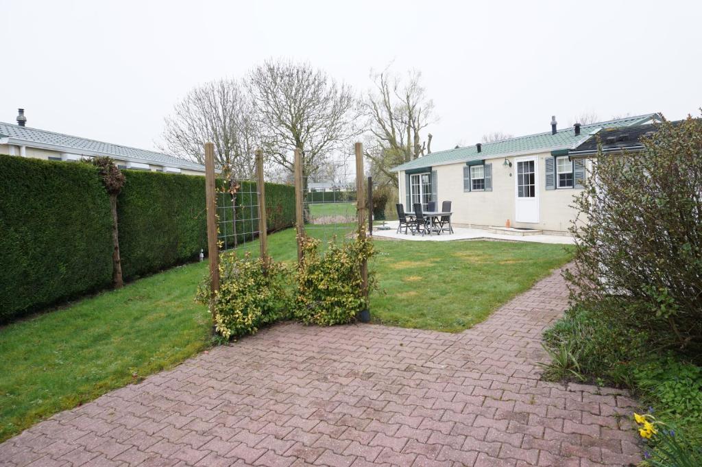 a backyard with a fence and a yard with a house at Kustverhuur, Groede, Paarlhof 53 in Groede