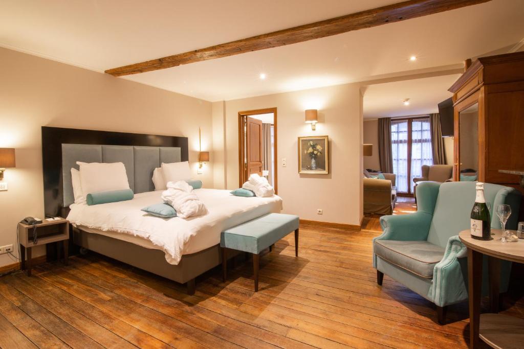 a bedroom with a large bed and a chair at Hotel de la Poste - Relais de Napoleon III in Bouillon