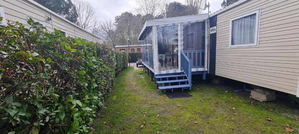 una casa con una ventana junto a una valla en Mobil home neuf 693 à la réserve 8 personnes avec terrasse couverte, en Gastes