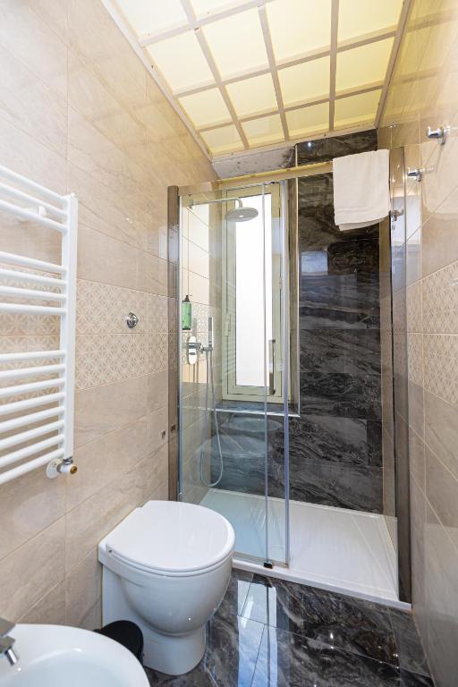 łazienka z toaletą i przeszklonym prysznicem w obiekcie Adriana sweet apartment w Rzymie