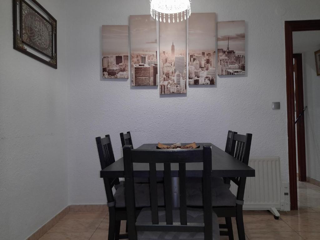 mesa de comedor con 4 sillas y lámpara de araña en sweet house close to airport, en El Prat de Llobregat