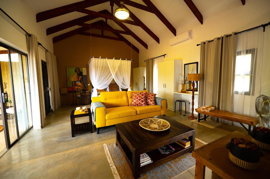 a living room with a yellow couch and a table at Oriole Bush Cottage in Hoedspruit
