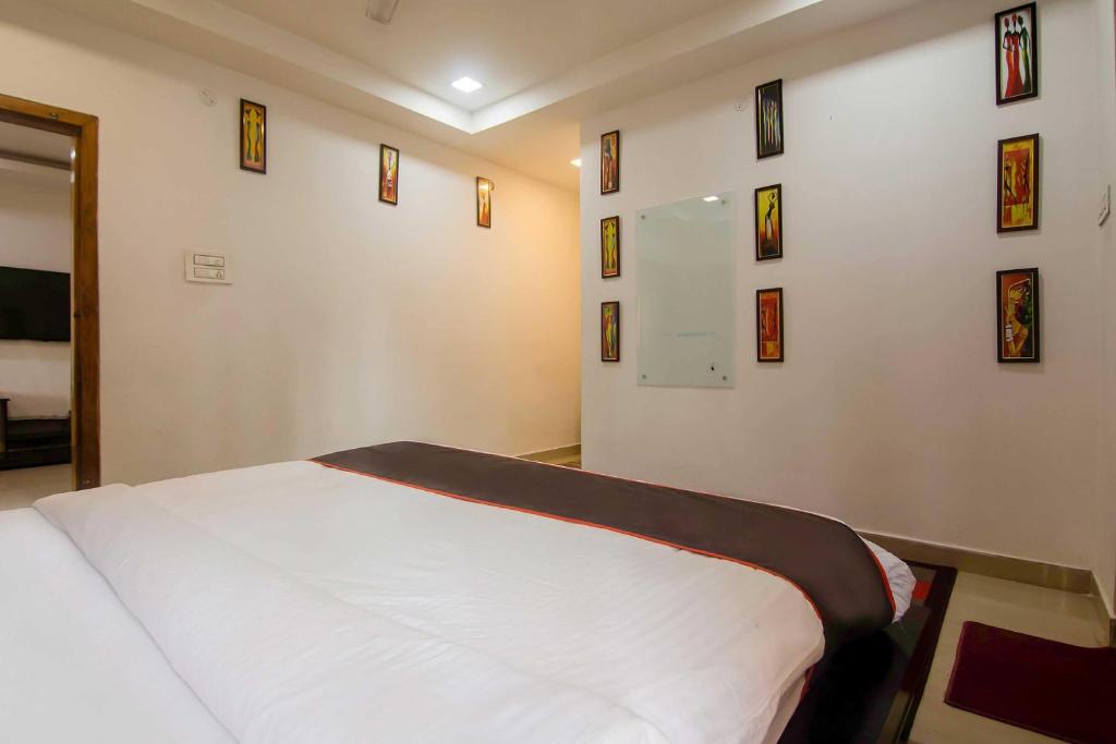 a bedroom with a white bed with pictures on the wall at Super Collection O The Blu Bell Nizarapar Path in Guwahati