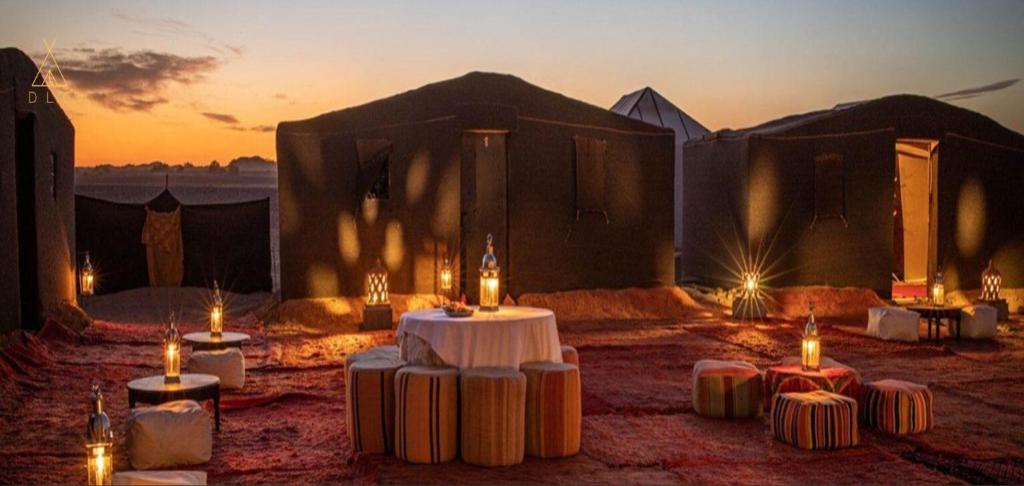 un gruppo di tavoli con candele di fronte a una tenda di Desert Luxury Camp a M'Hamid