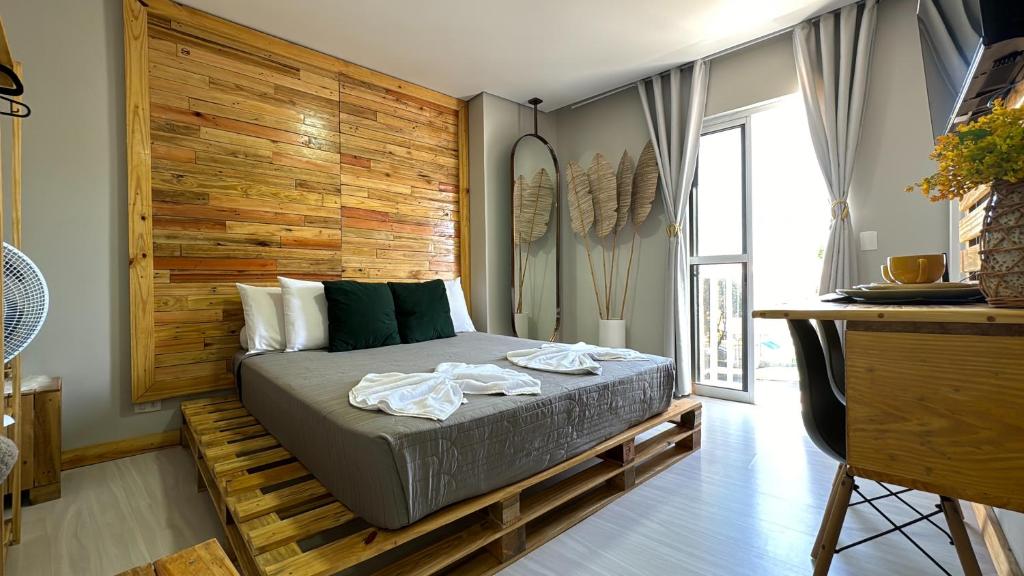1 dormitorio con 1 cama con pared de madera en 22- Studio SPA luxo en Curitiba