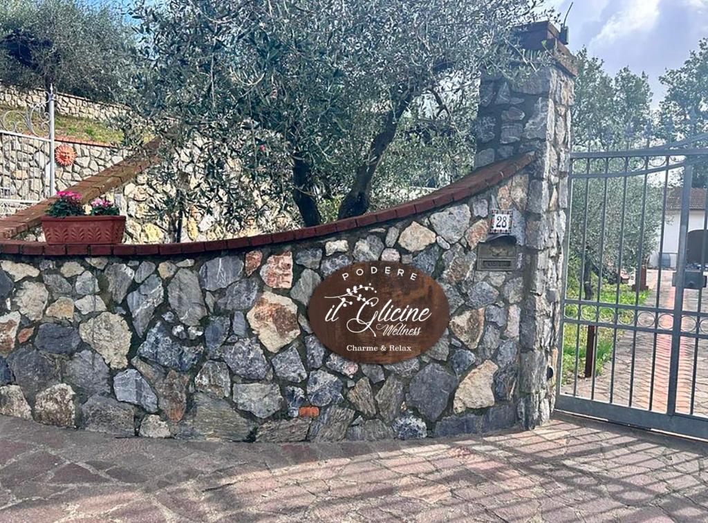 eine Steinmauer mit einem Schild am Zaun in der Unterkunft Podere il Glicine Wellness Charme & Relax in Fresonara