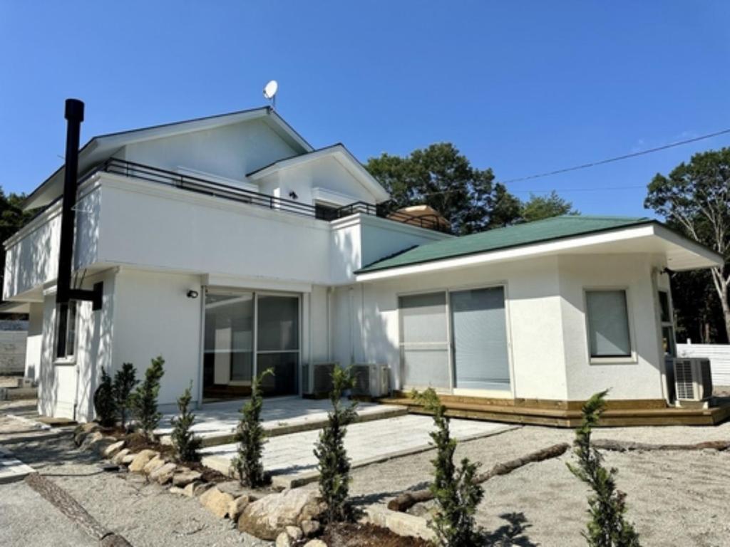 ein weißes Haus mit Bäumen davor in der Unterkunft Nasu Kogen Yamagoya - Vacation STAY 29353v in Shiozawa