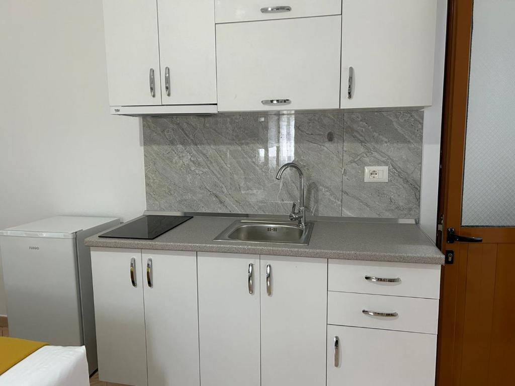a kitchen with white cabinets and a sink at Kiki’s Rooms in Vlorë