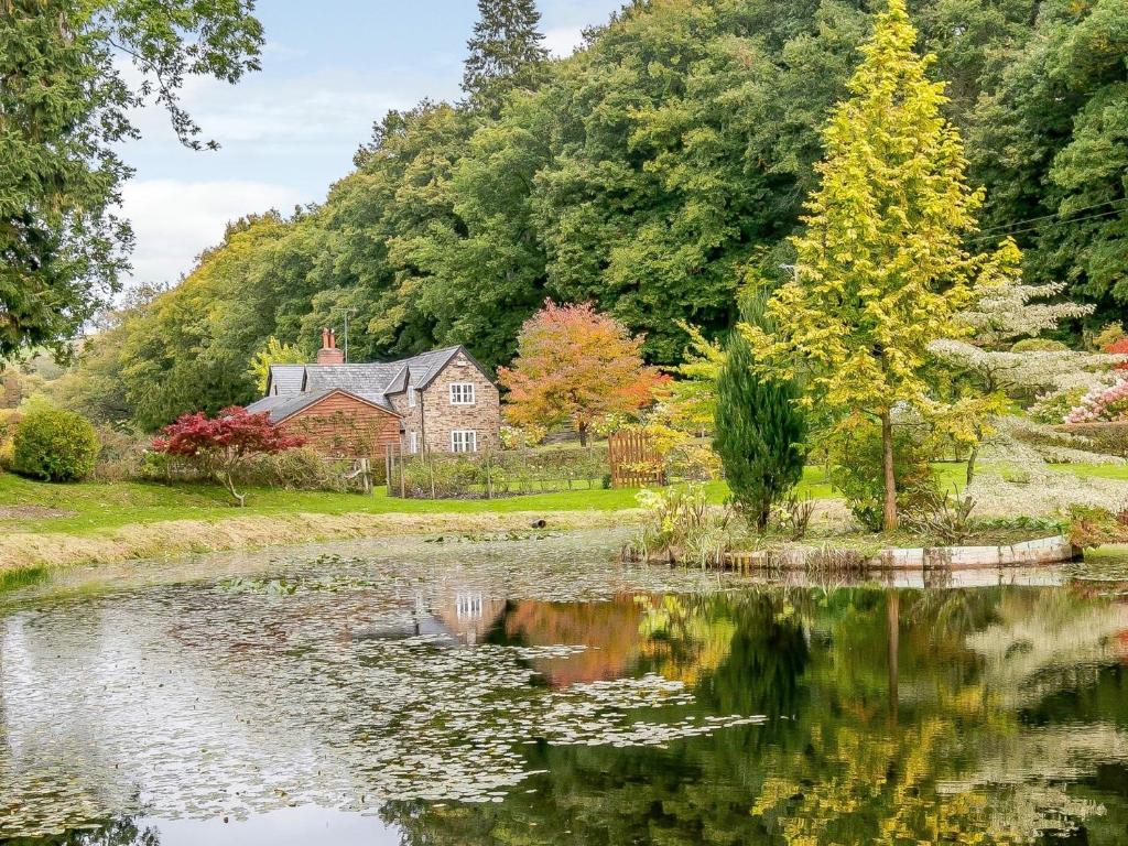 a house and a pond in front of a house at 3 Bed in Presteigne 78336 in Evenjobb