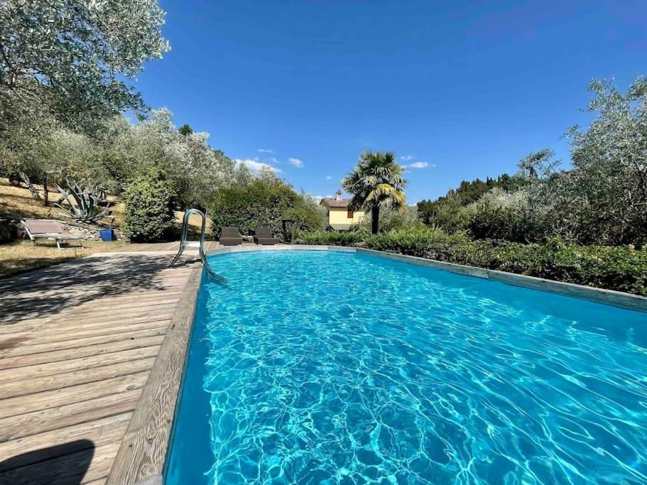 een groot blauw zwembad met een houten terras bij Stone house with pool in Montefiridolfi