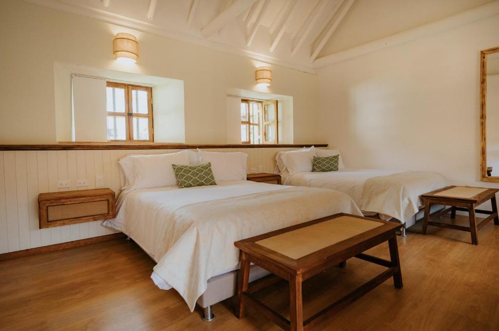 a bedroom with two beds and a table in it at Hotel La Corada in Villa de Leyva