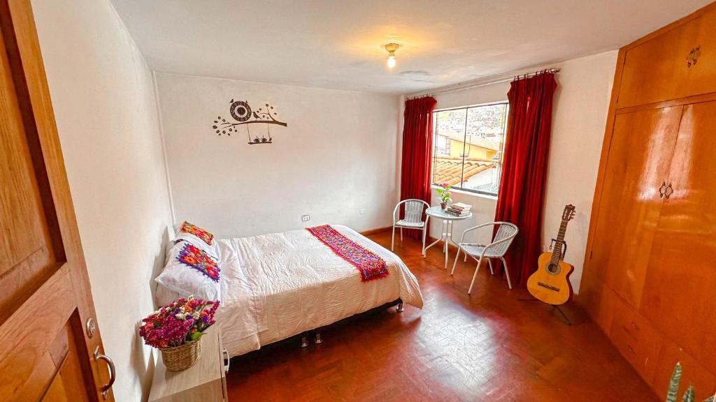 a bedroom with a bed and a table and a guitar at Apart Hotel de Alegria in Cusco