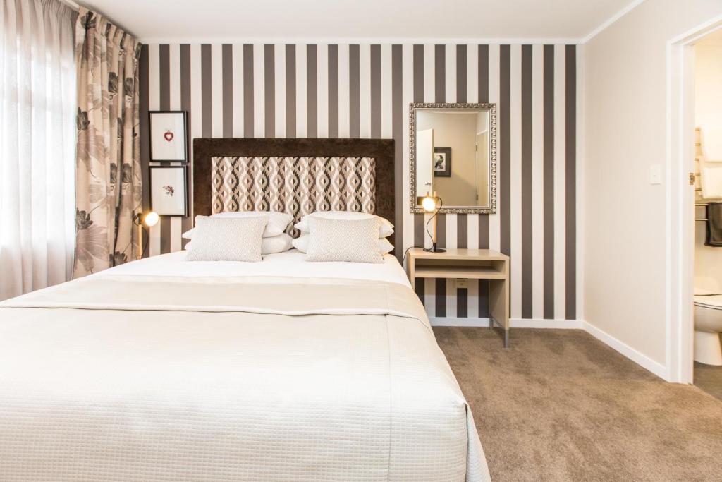 a bedroom with a large white bed and a mirror at ASURE Destiny on Fitzherbert Motel in Palmerston North