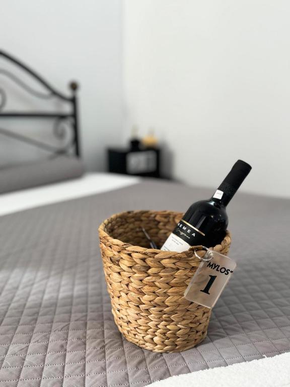 a bottle of wine in a basket on a bed at O Mylos in Ermoupoli