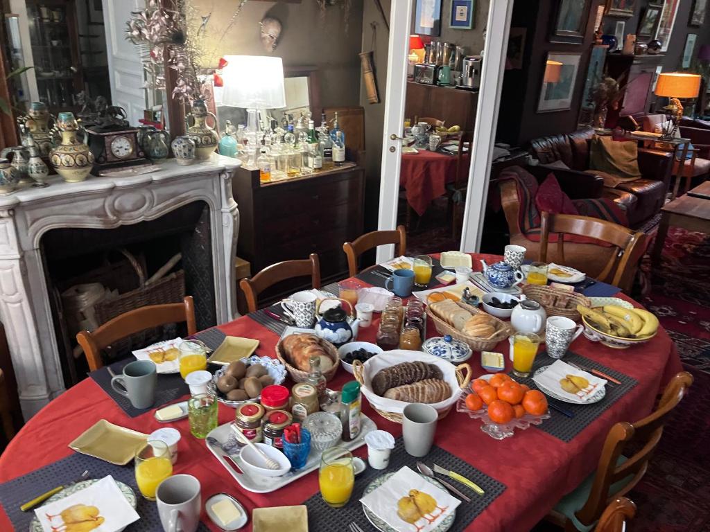 una mesa con comida para el desayuno y bebidas en ella en Camera et Caetera Chambres d'hôtes B&B en Roubaix