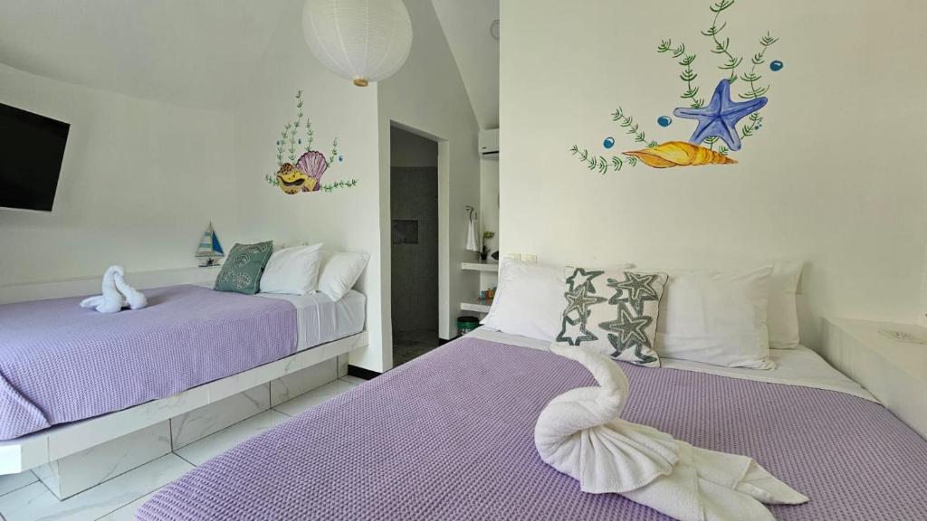 sypialnia z 2 łóżkami z fioletową pościelą i łabędziem w obiekcie Alborada Boutique Stay w mieście Uvita