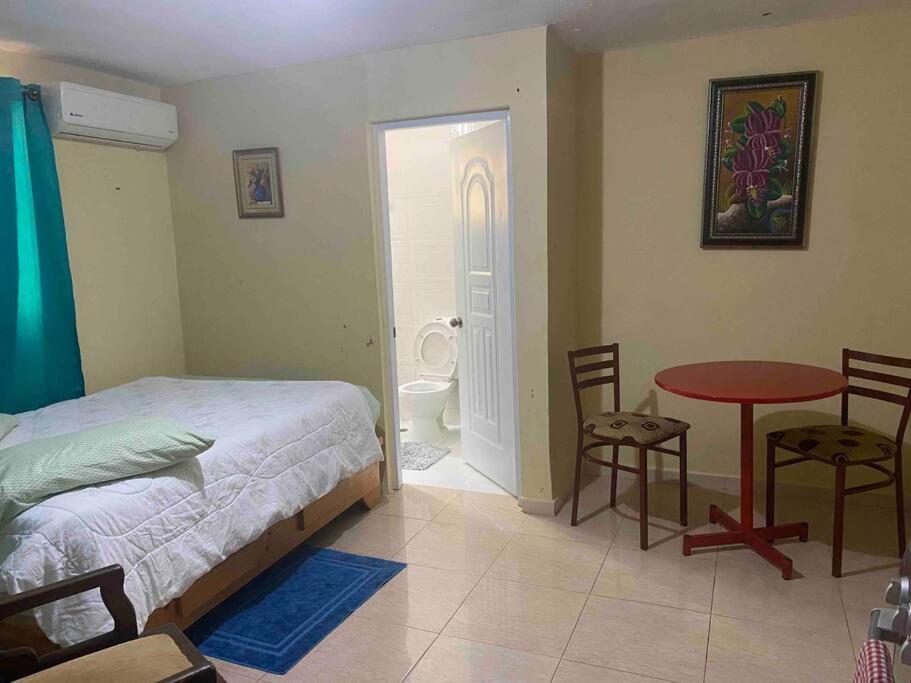 a bedroom with a bed and a table and a bathroom at apartaestudio santo domingo a 40 minutos playa. in Los Tres Brazos