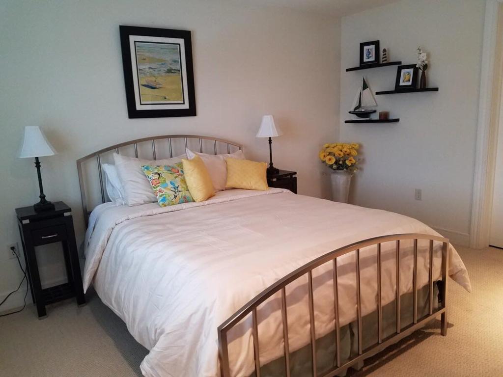 una camera da letto con un letto grande con lenzuola e cuscini bianchi di Corner suite at Peninsula Bay Resort awaits a Traverse City