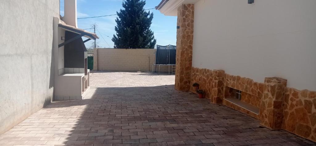 Une allée en briques avec un bâtiment et un arbre dans l'établissement Pandora Casa Rural en Madrigueras, à Albacete