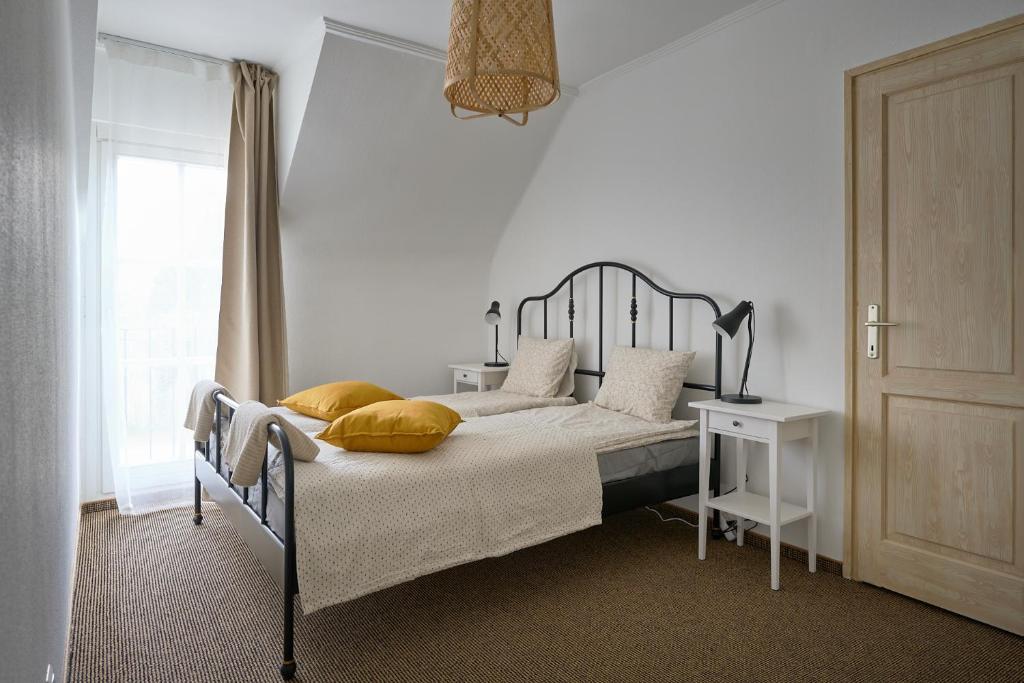 een slaapkamer met een bed met gele kussens en een raam bij Kúria apartmanház in Bük