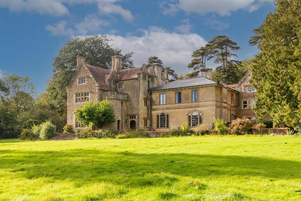 an old castle on a grassy field at 9 Bedrooms Grand Manor House Near Bath, Sleeps 26 in Seend