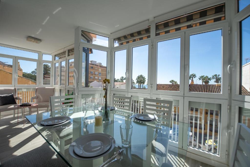 a dining room with a glass table and windows at Nordik Apartments Urban - Bellavista "Moskenes" in Málaga