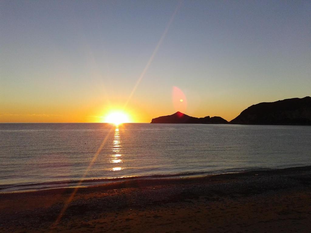 a sunset on the beach with a mountain in the background at Marilena's Beach House in Agios Georgios Pagon