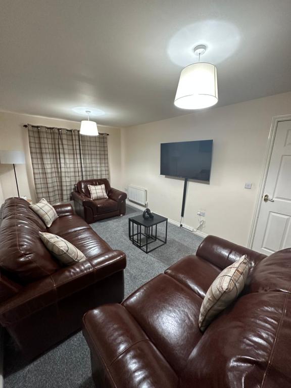 a living room with two leather couches and a flat screen tv at City Airport Apartment in Wythenshawe