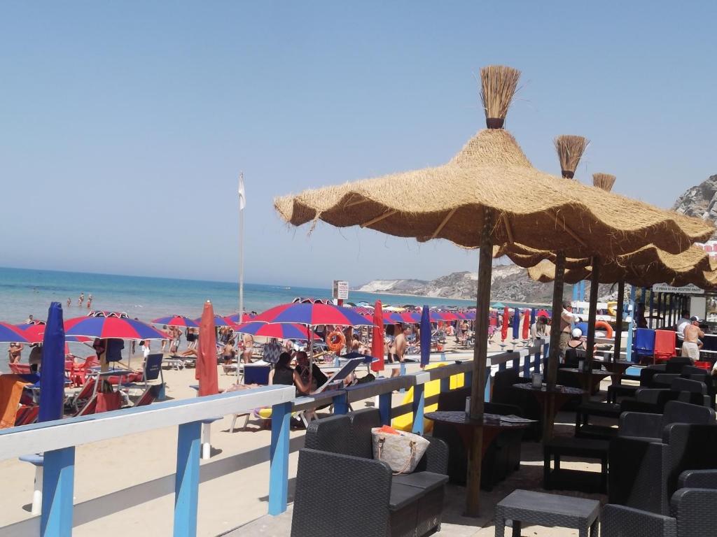 - une plage avec un bouquet de chaises et de parasols dans l'établissement Siculiana Marina - oasi wwf, à Siculiana Marina