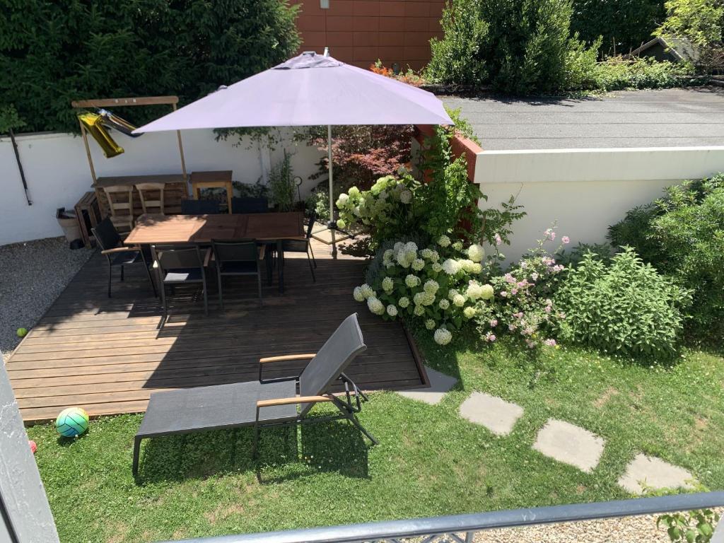 une terrasse en bois avec une table et un parasol dans l'établissement Charmante maison de ville avec jardin et piscine, à Auxerre