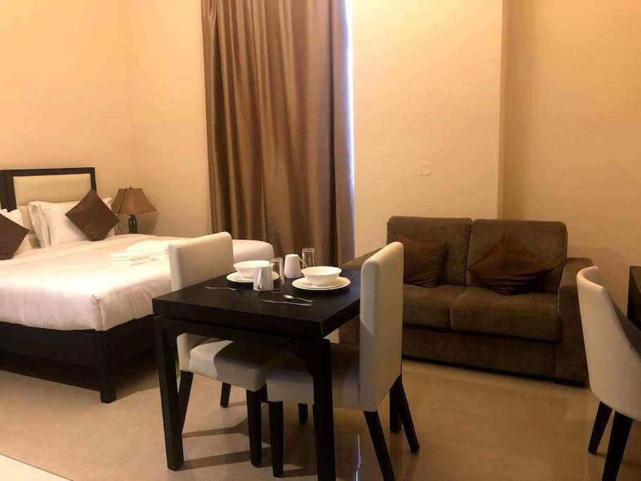 een kamer met een bed, een tafel en een bank bij Luxury Studio/Apartment in JVC in Dubai