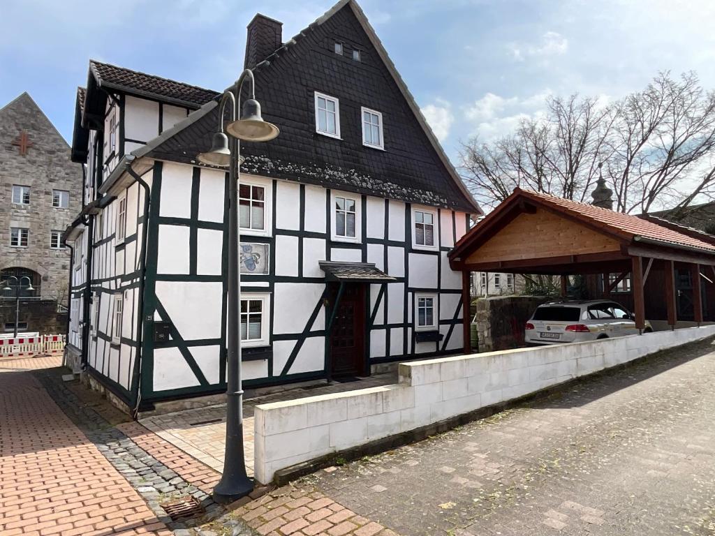 a black and white building with a pavilion next to a street at Urig, gemütliches Fachwerkhaus in Korbach